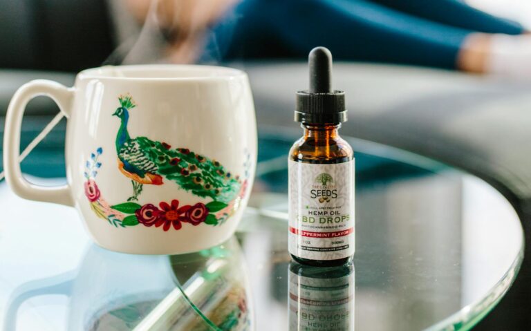 A person enjoys CBD oil and a hot drink on a glass table indoors, creating a cozy setting.